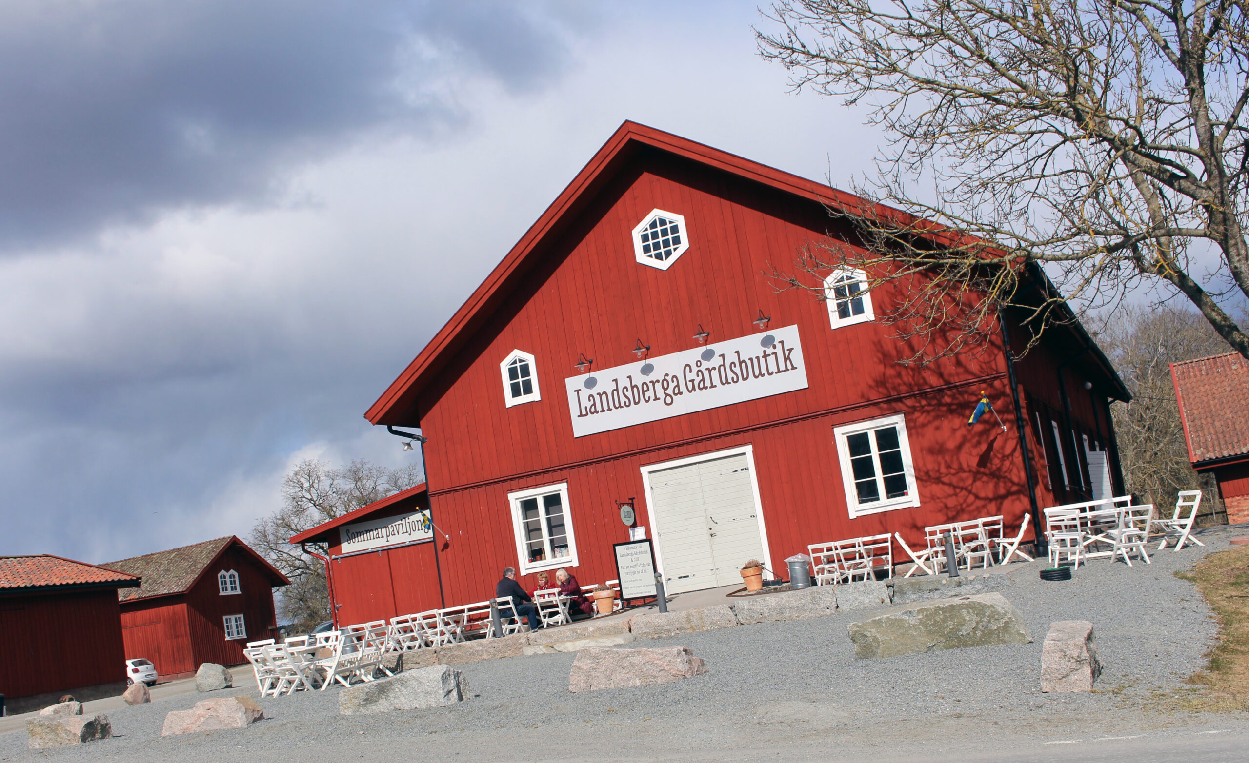 Frontfasad på Landsberga gård med uteservering och stenparti.